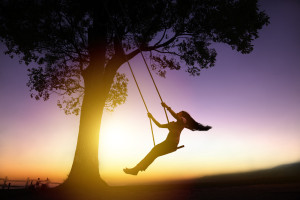 Happy -Woman-On-A-Swing With Sunset Backgroun